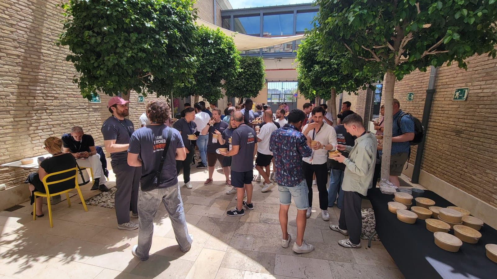 Participants eat lunch together under the trees in the Las Naves courtyard, June 2026.
