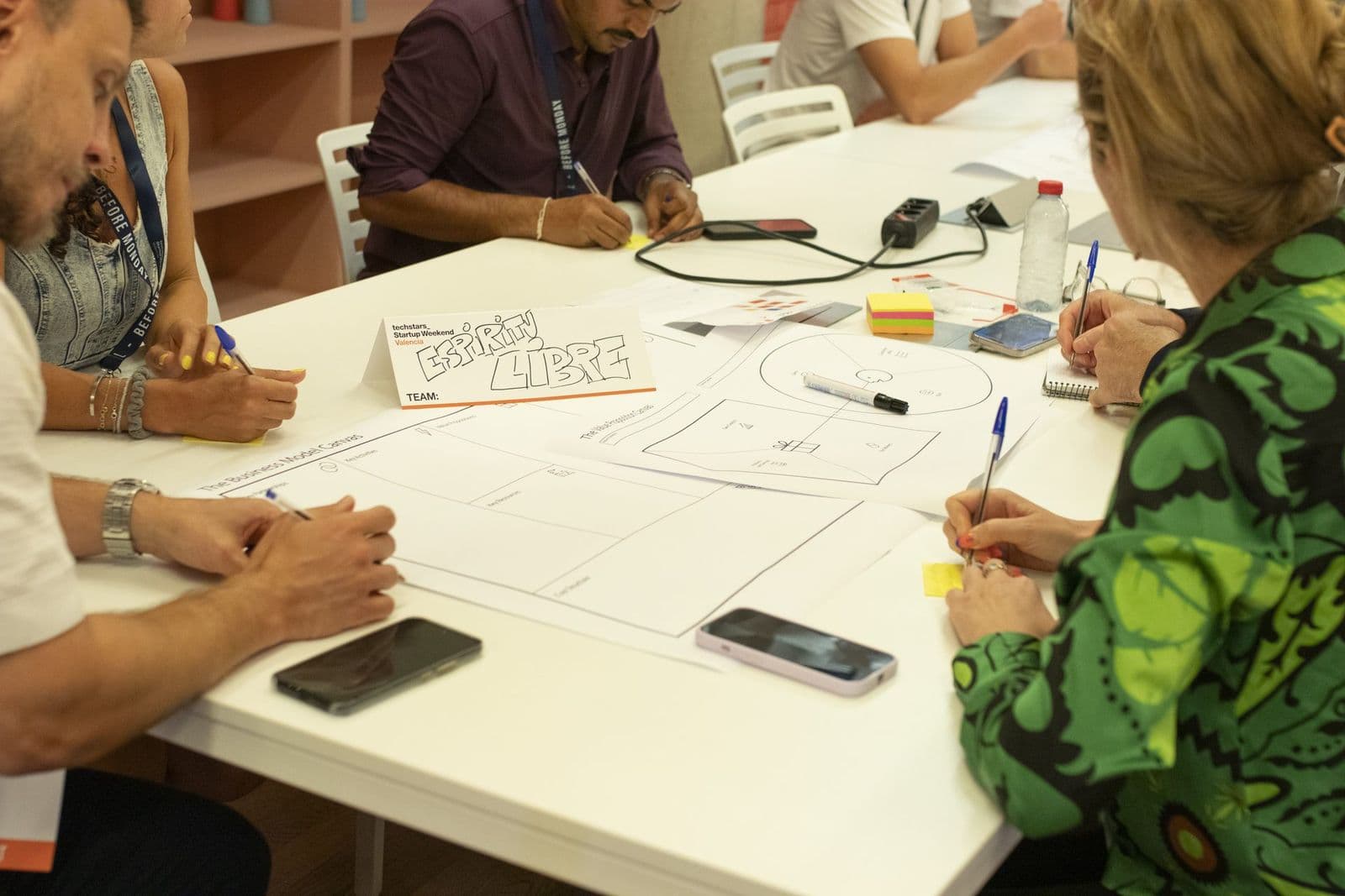 A team works through a business model canvas on paper at their table during the June 2026 edition.