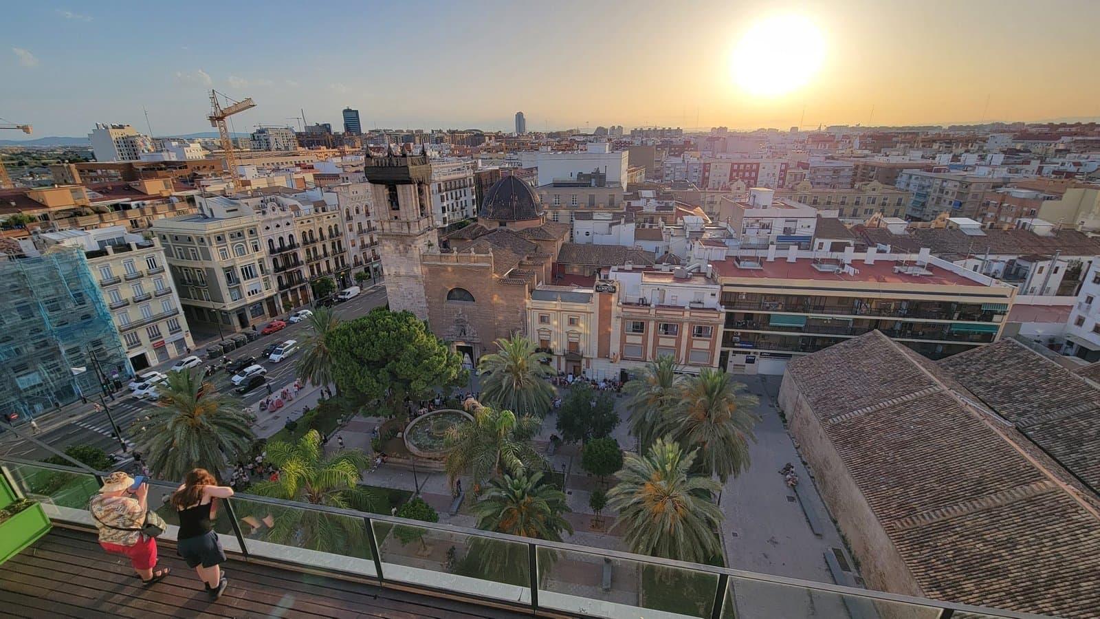 View from the Las Naves terrace over Valencia rooftops at sunset, with palm trees and attendees looking out over the city, during the June 2026 edition.